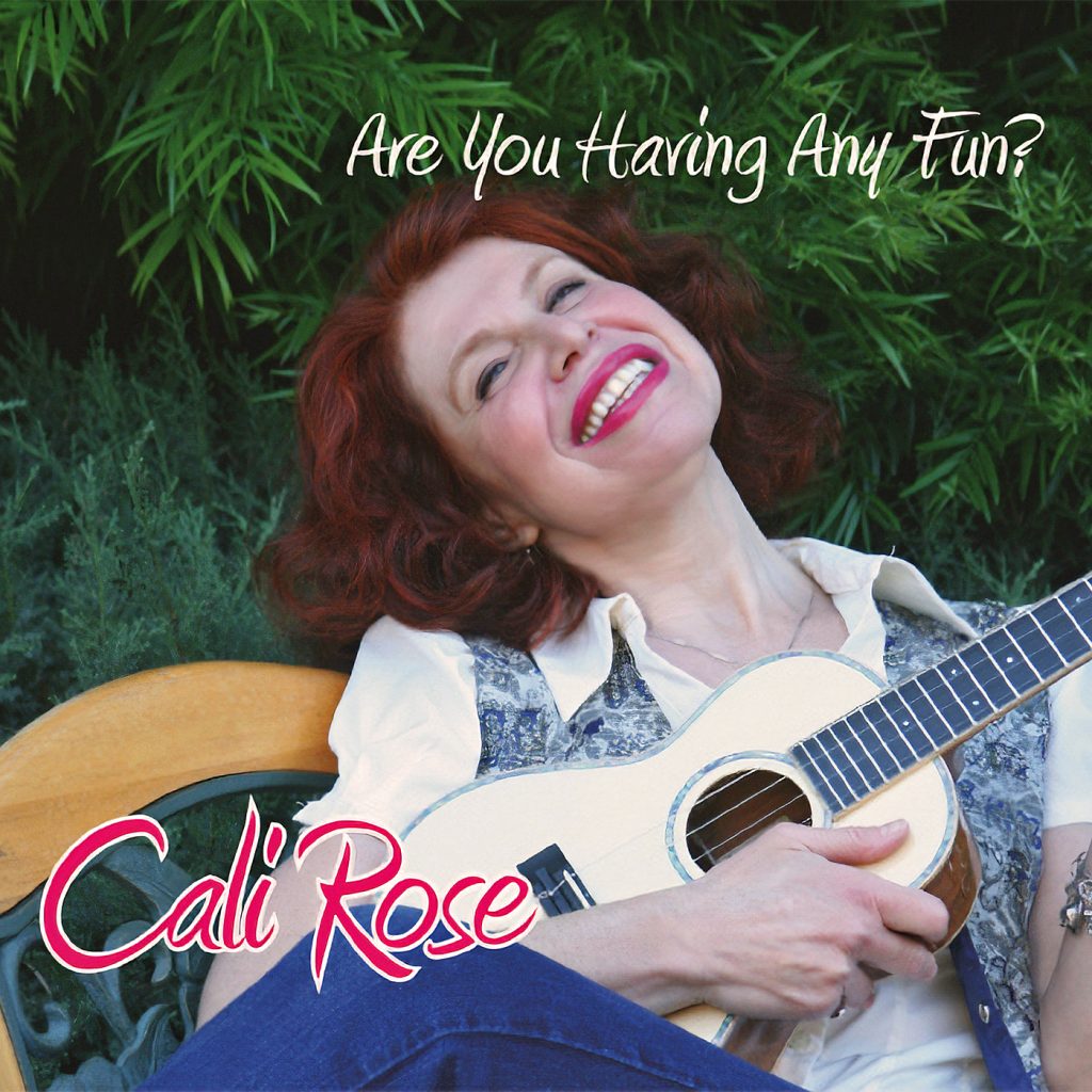 Front cover of an album features a woman with red hair playing ukulele reclining on a bench and smiling