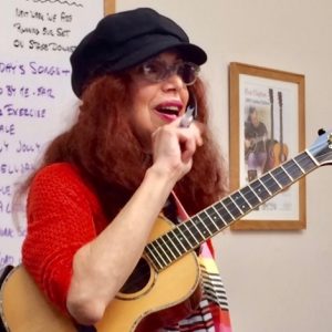 A woman with a microphone and a ukulele