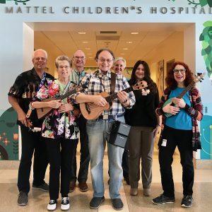 Seven people holding ukuleles at a hospital building