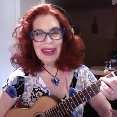 a woman with red hair, glasses, and a ukulele