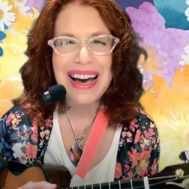 a woman holding a ukulele against a background of flowers